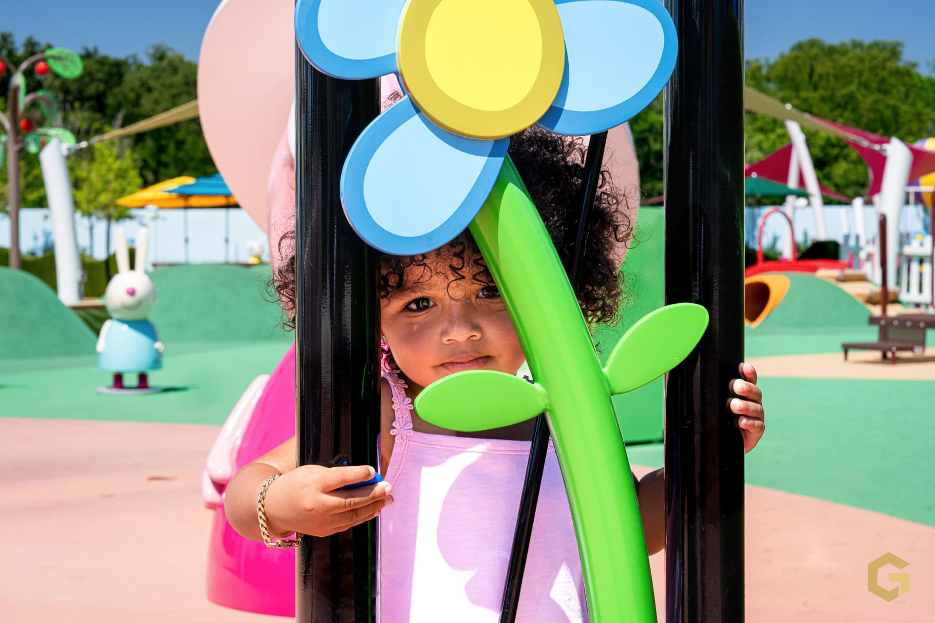 Birthday girl peeking through a colorful flower at the playground