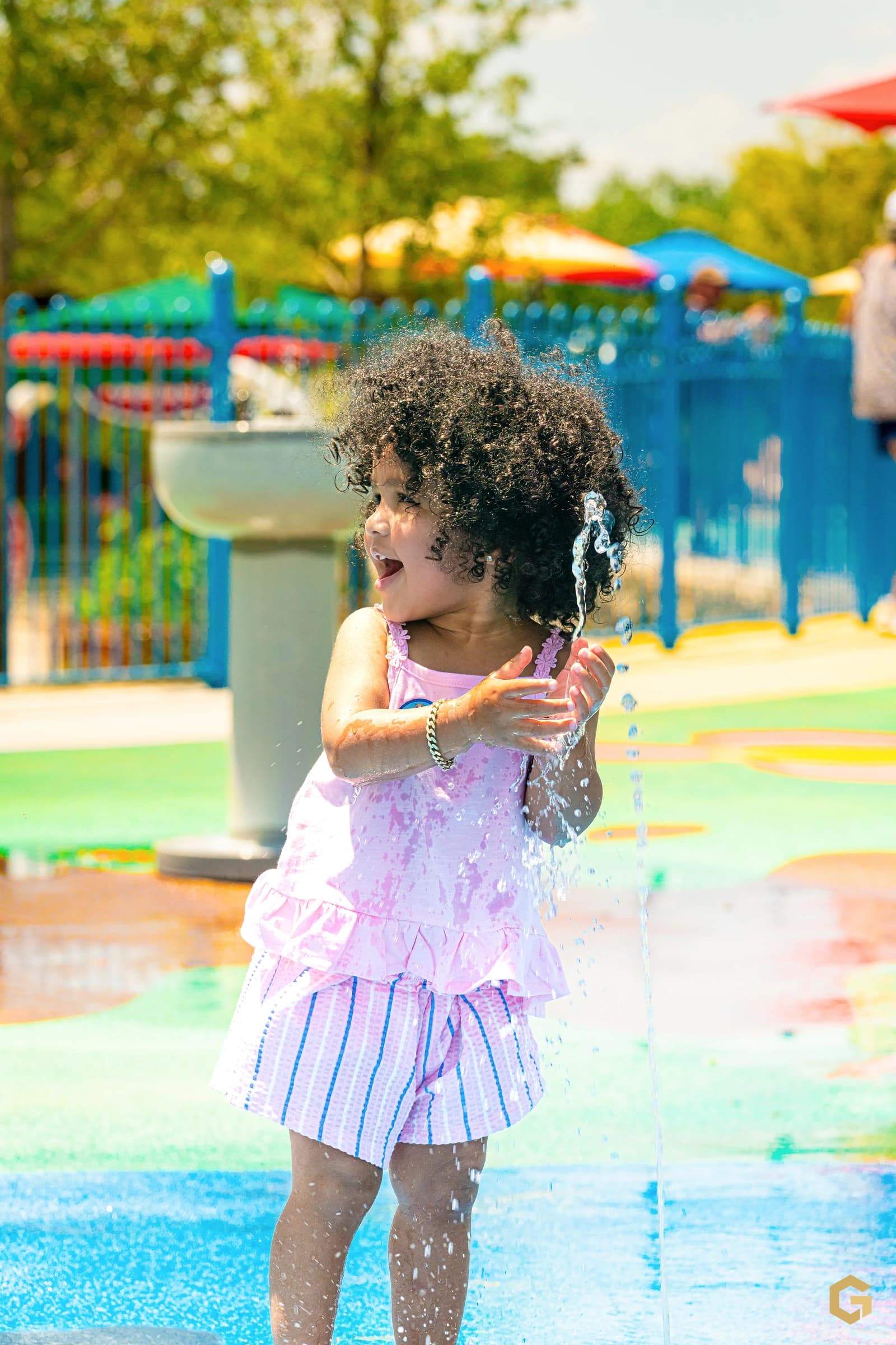 Birthday girl laughing as she catches a stream of water