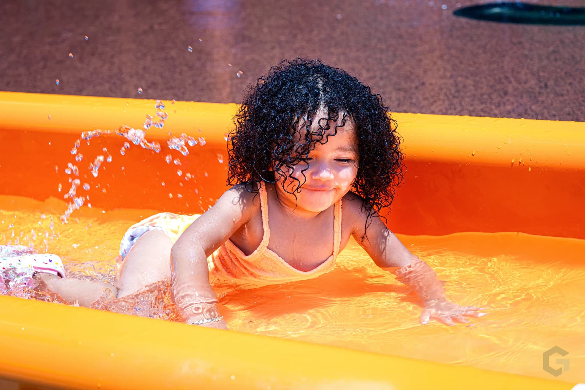 Birthday girl splashing through a bright orange water feature