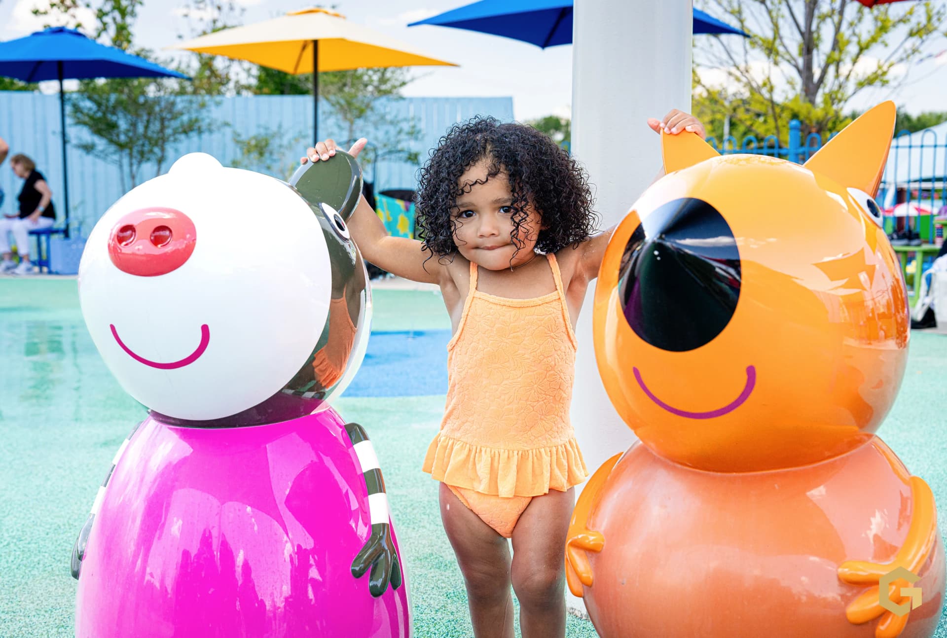 Birthday girl posing between two colorful playground characters