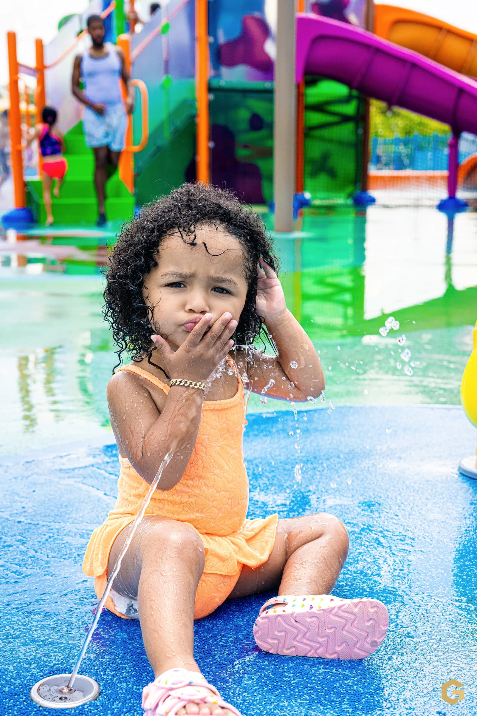 Birthday girl blowing a kiss while seated in the splash pad