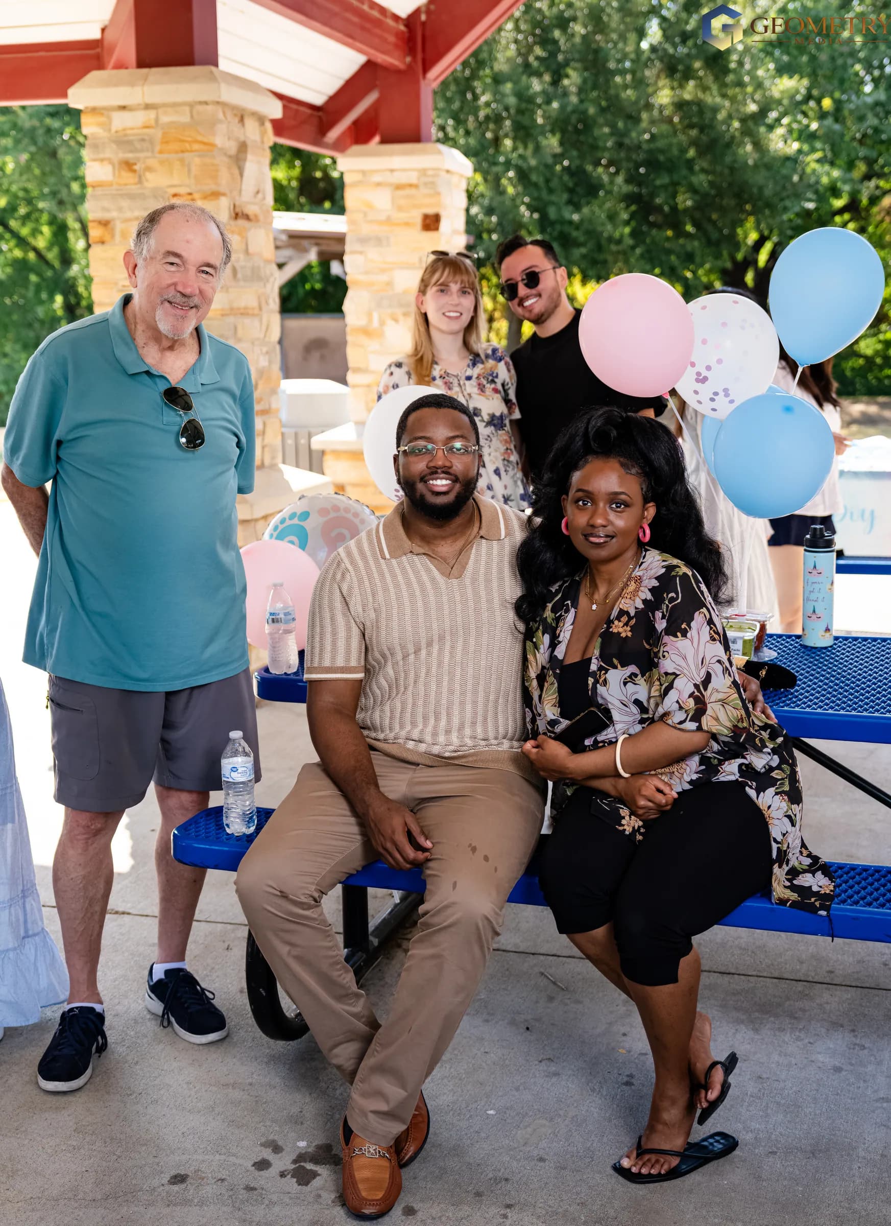 Guests gather for a portrait with pink-and-blue balloons