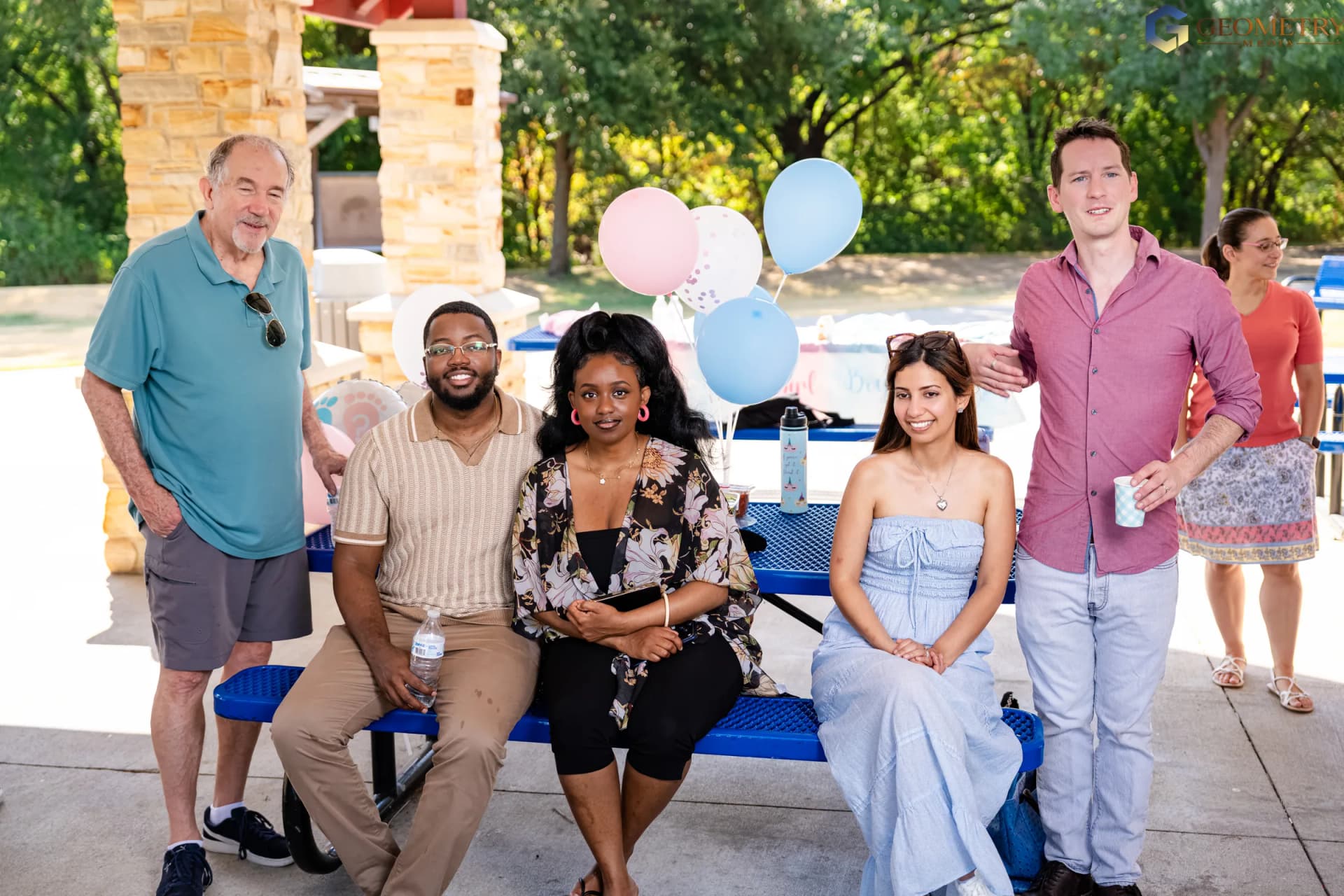 Friends and family pose together with pink-and-blue balloons