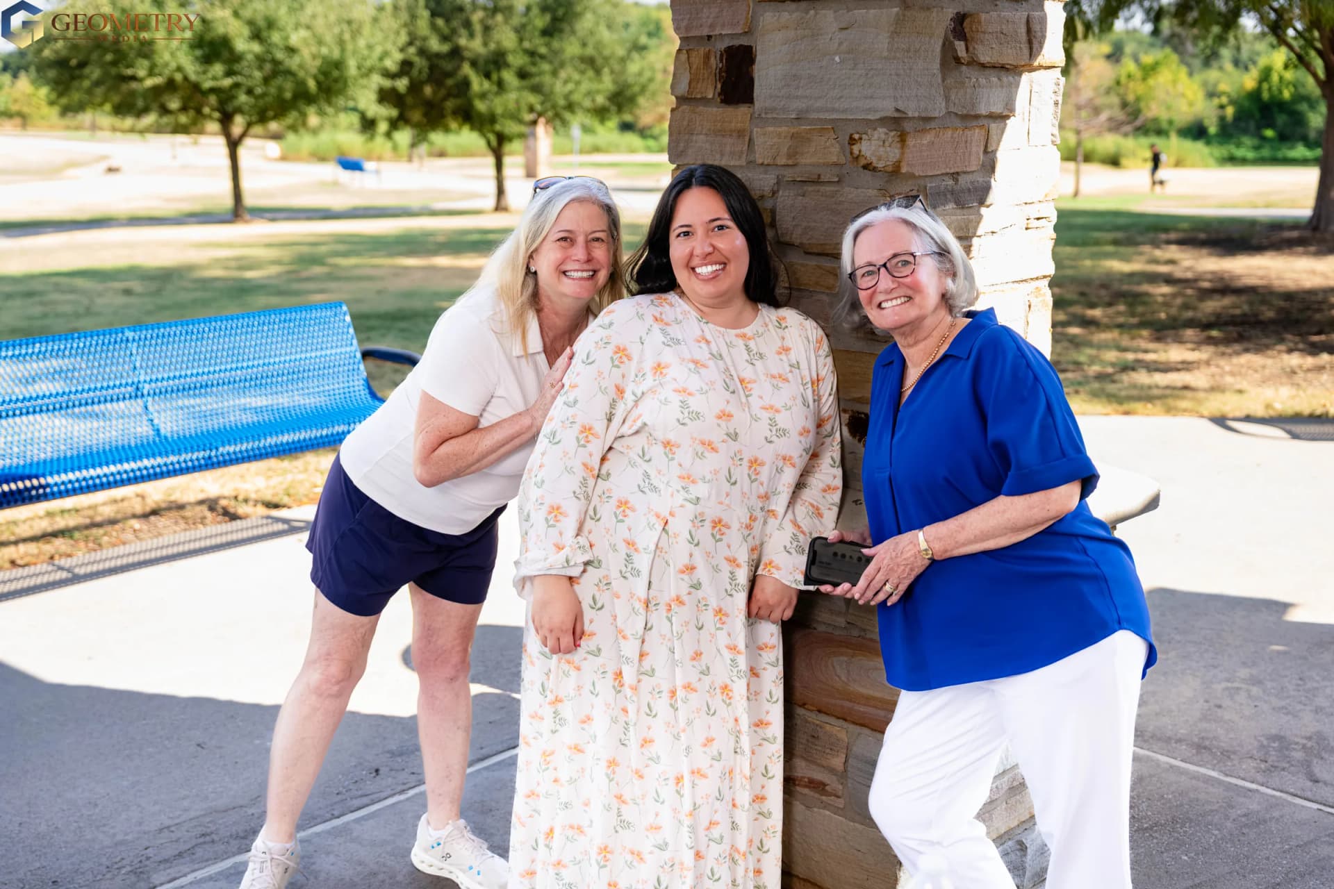 Three guests share a joyful portrait beside the stone pavilion