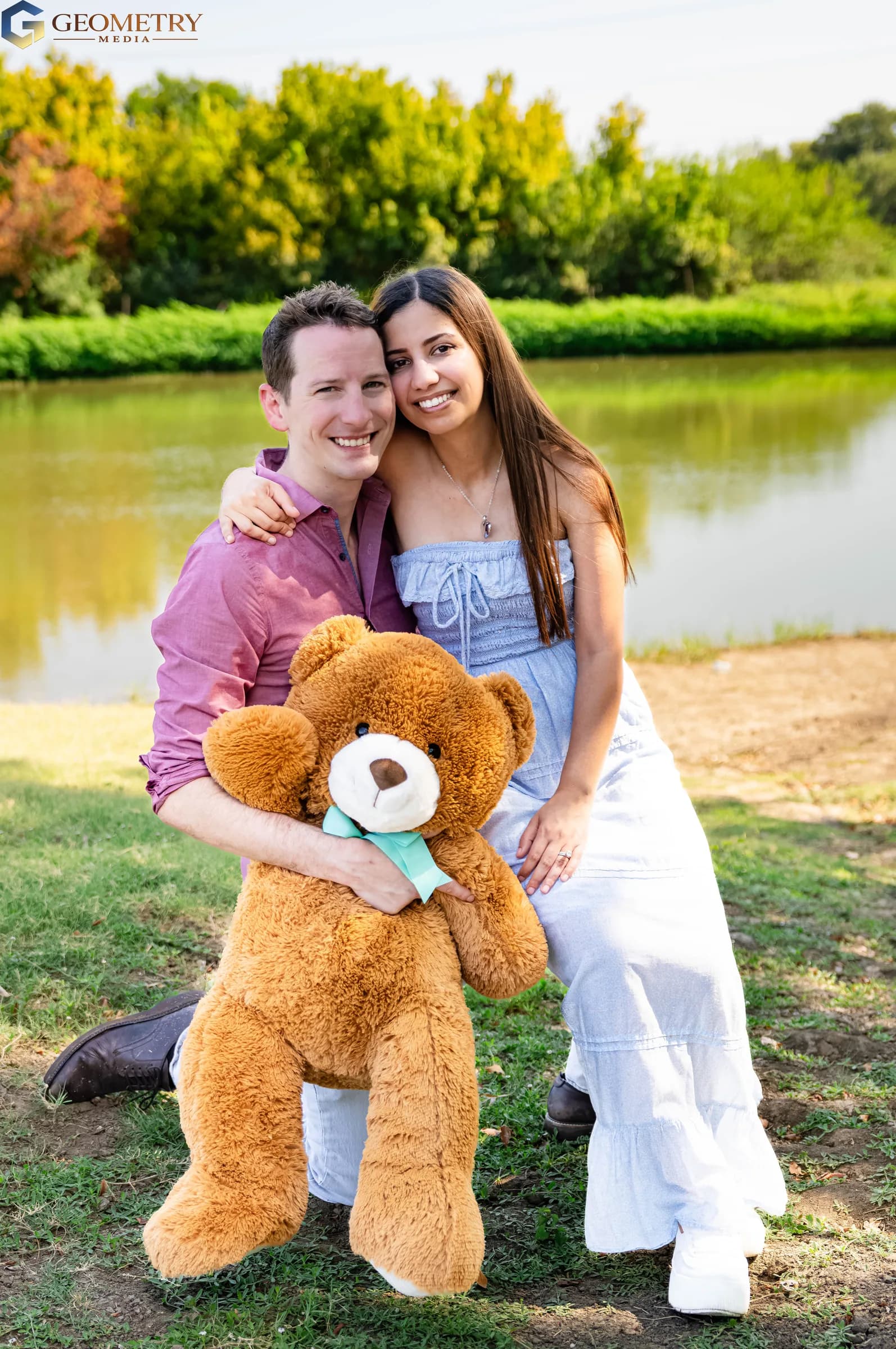 Close portrait of the expectant parents smiling with their teddy bear