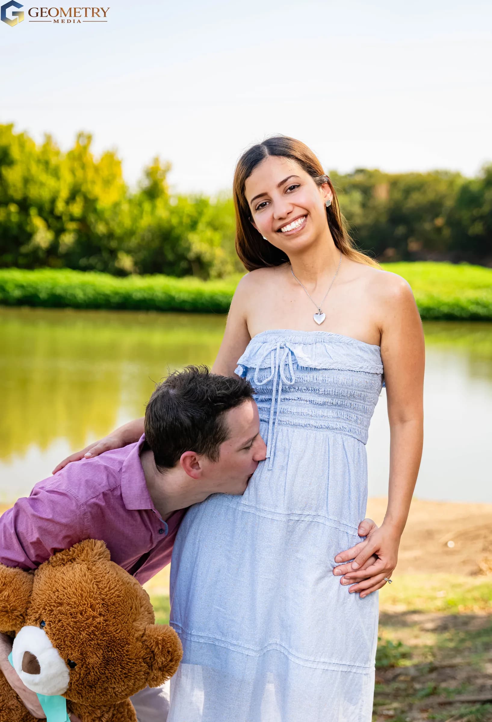 Mother smiles in a close maternity portrait as the father kisses her baby bump